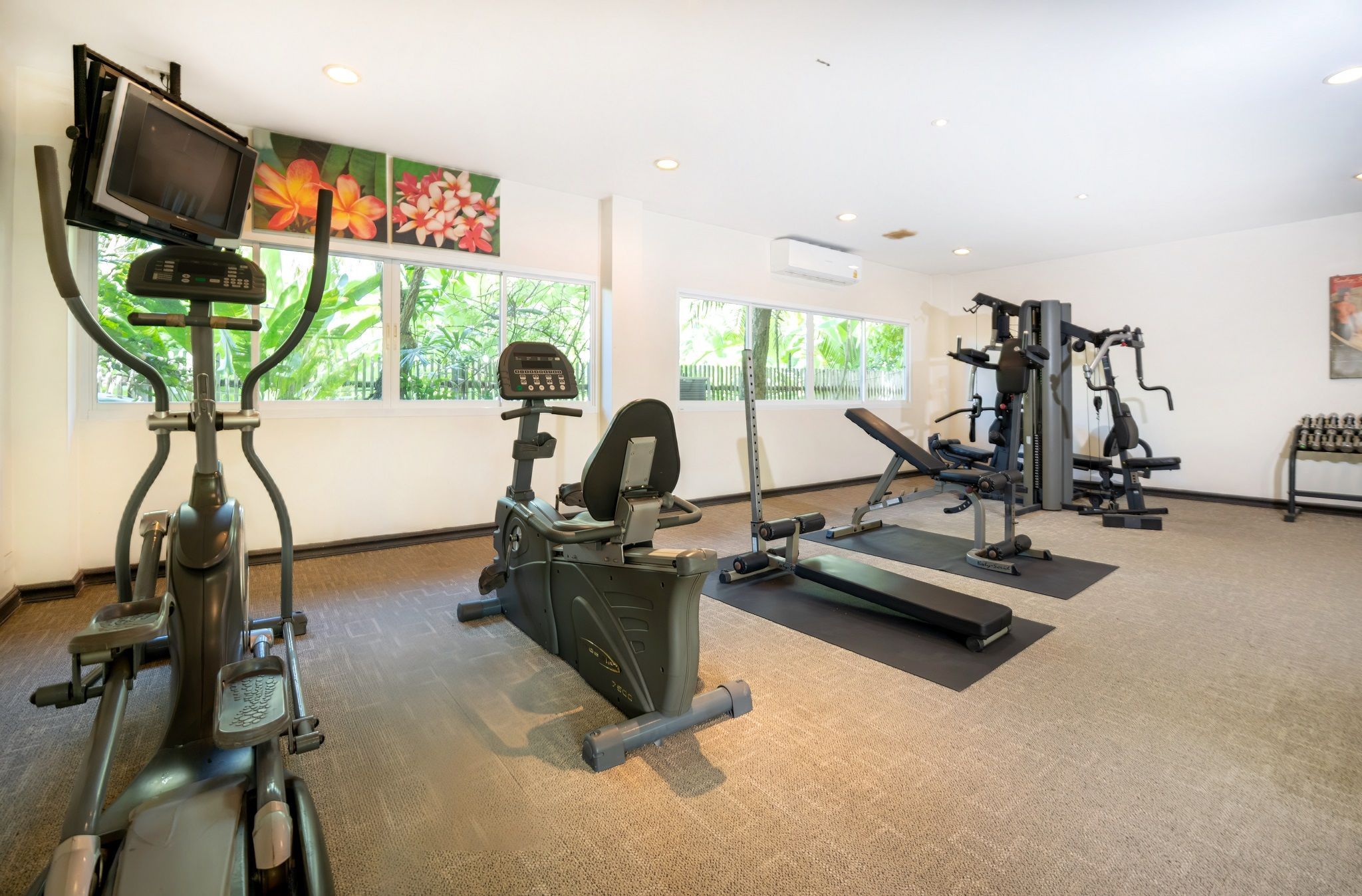 Une salle de sport équipée de machines de cardio, de matériel de musculation et de tapis de sol pour les exercices.