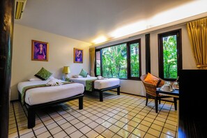 Habitación de hotel con dos camas, una mesa de comedor, televisión y ventanas amplias con vistas a zonas verdes.