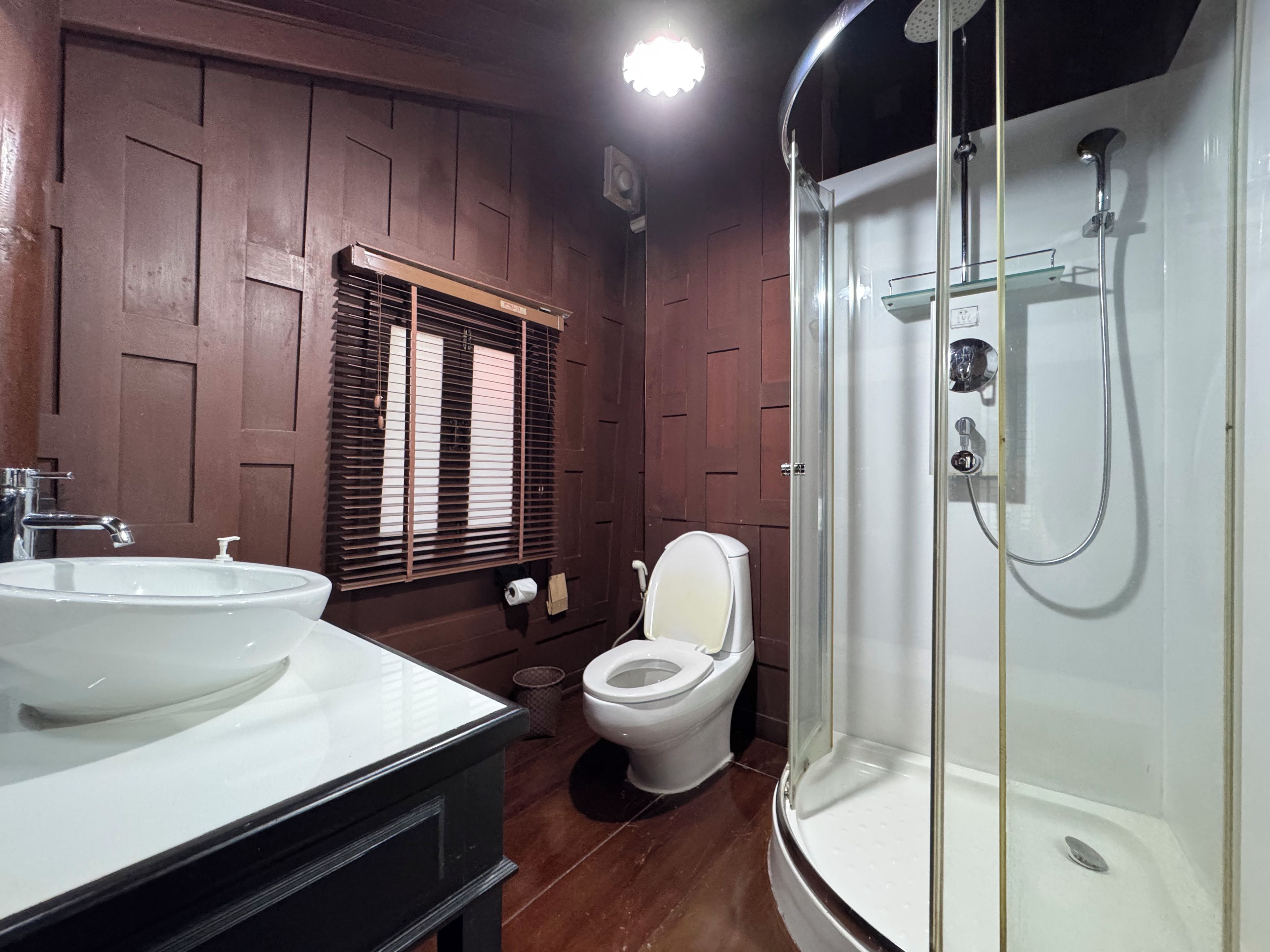 Un baño con lavamanos blanco, inodoro y ducha con cerramiento de vidrio.