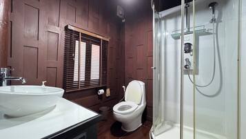 Un baño con lavamanos blanco, inodoro y ducha con cerramiento de vidrio.