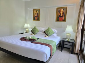 A hotel room with a large bed, two nightstands, a lamp, and two wall-mounted paintings. - Baan Amphawa Resort & Spa (Amphawa)