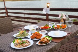 A table set with various dishes, a sign indicating a no-leaning policy, and a lamp post in the background. - Baan Amphawa Resort & Spa (Amphawa)