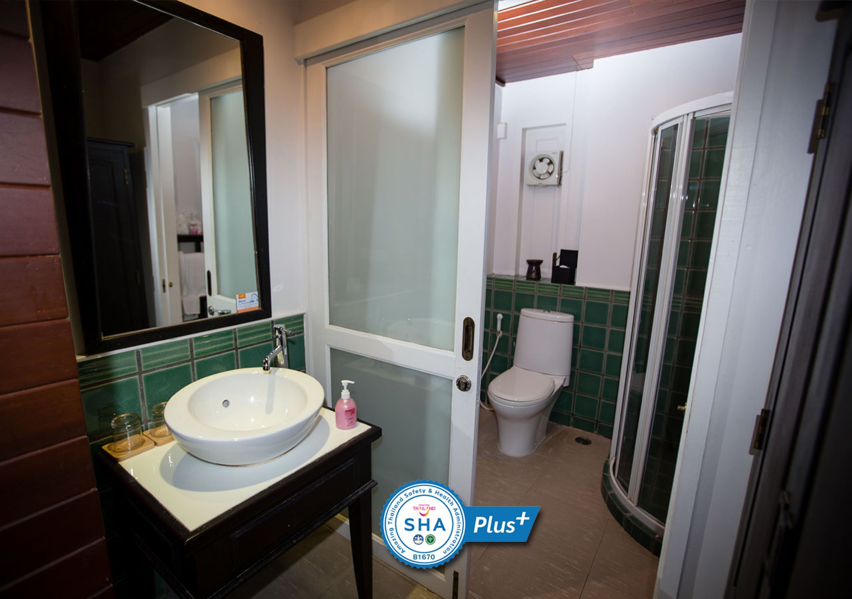 Un baño con lavamanos blanco, espejo, inodoro y zona de ducha.