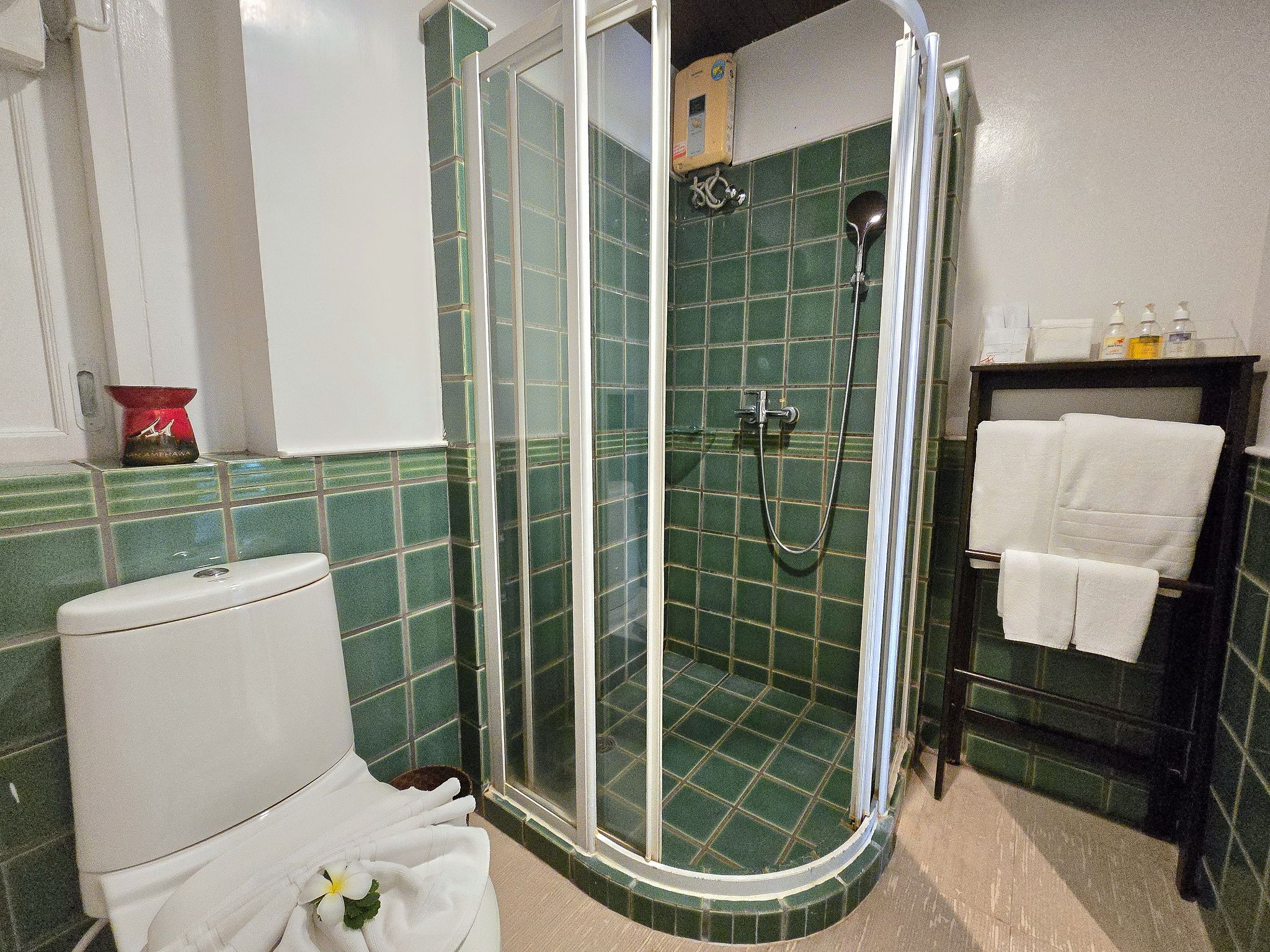 Un bagno con doccia vetro, un water e un lavandino con porta asciugamani.