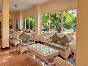 A room with wicker furniture, large windows, and a tiled floor. - Baan Amphawa Resort & Spa (Amphawa)