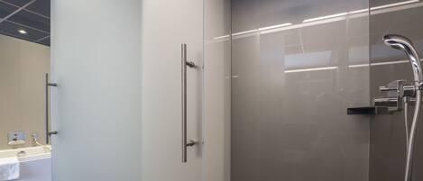 A modern bathroom with a glass shower enclosure, a visible bathtub, and a tiled floor.