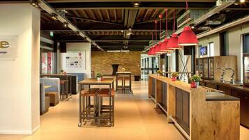 A modern restaurant with a wooden bar, seating area, and a stone wall in the background.
