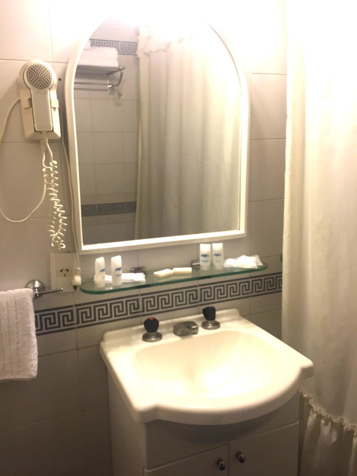 A bathroom with a sink, mirror, and a hairdryer on the wall.