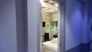 Un dormitorio con pared de piedra, cama, mesita de noche y espejo.