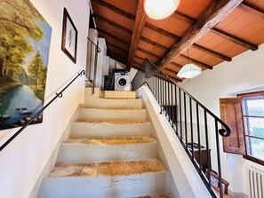 A staircase with a wooden ceiling and a view of a river painting on the wall. - B&B Molenda (Città di Castello)