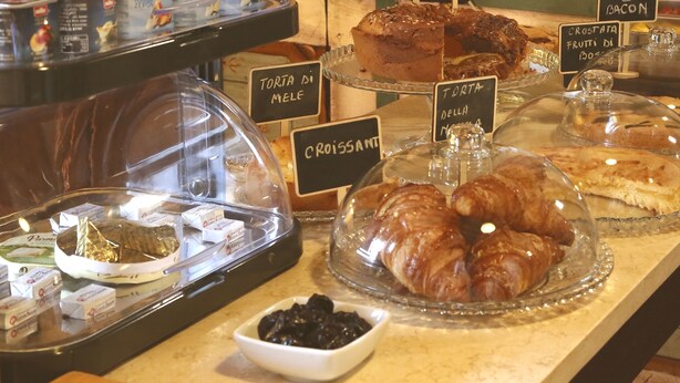A bakery display with various pastries and desserts, including croissants and cakes, with labels in Italian. - B&B Molenda (Città di Castello)