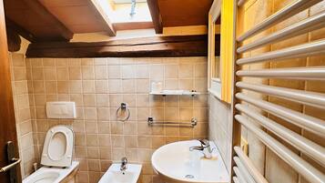 Un baño con inodoro, bidé, lavabo y un perchero para toallas.