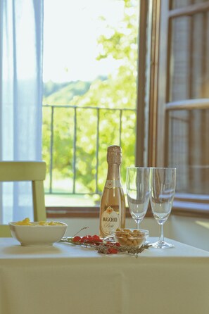 A table with a bottle of Maschio Prosecco, two glasses, a bowl of fruit, and a bowl of nuts. - B&B Molenda (Città di Castello)