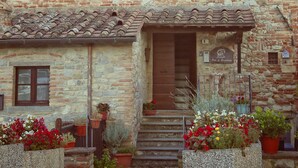 A stone building with a tiled roof, a wooden door, and potted plants in front. - B&B Molenda (Città di Castello)