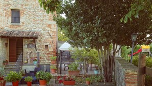 A stone building with a tiled roof, outdoor seating, and potted plants. - B&B Molenda (Città di Castello)