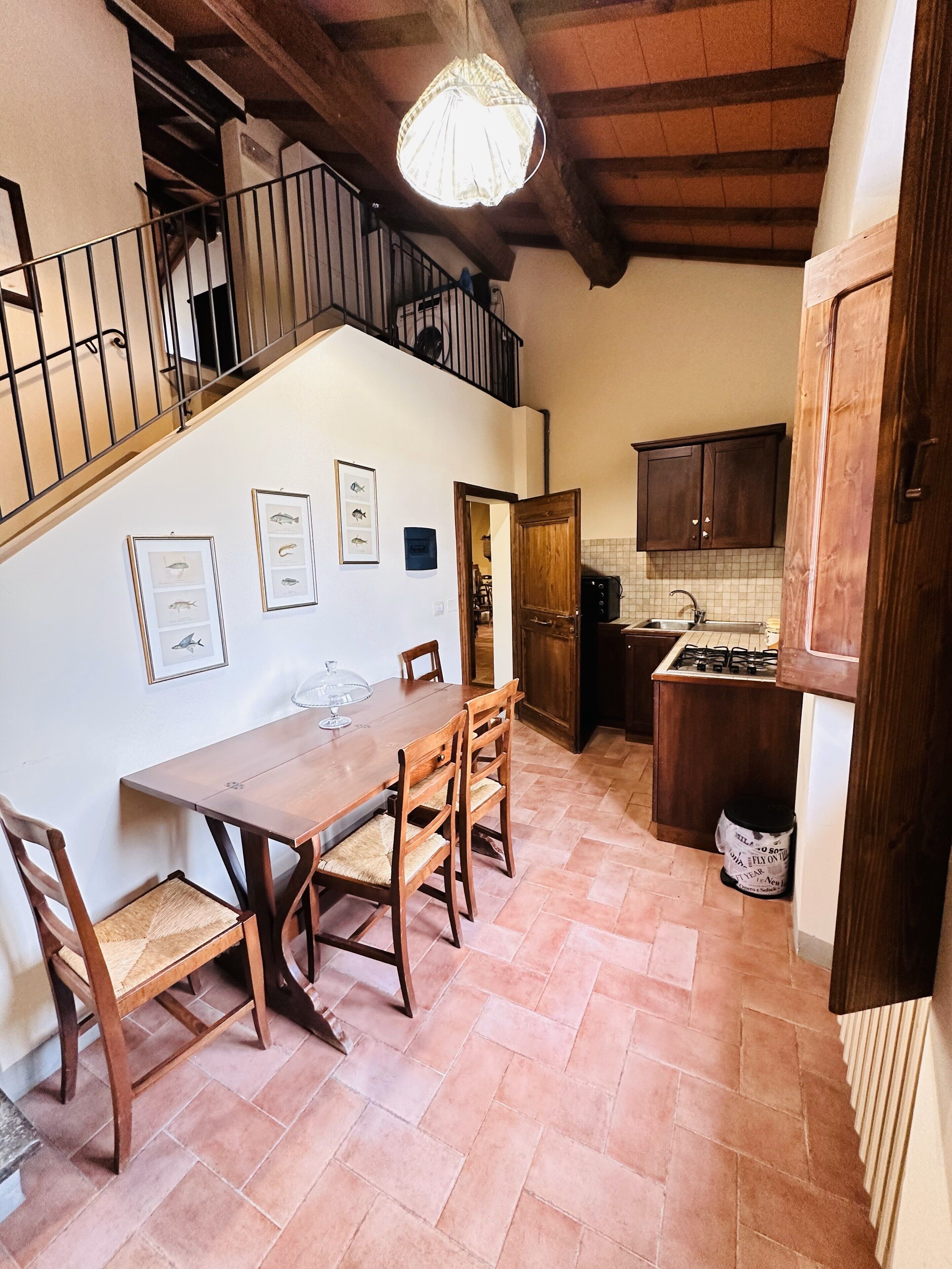 Ein Essbereich mit Holztisch und -stühlen, eine Treppe und eine Küche mit Holzschränken.