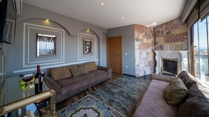 A living room with a sofa, a fireplace, and a stone wall. - Holiday Business Otel (Istanbul)
