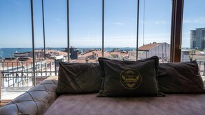 A bed with two pillows, a view of the cityscape, and a balcony railing. - Holiday Business Otel (Istanbul)