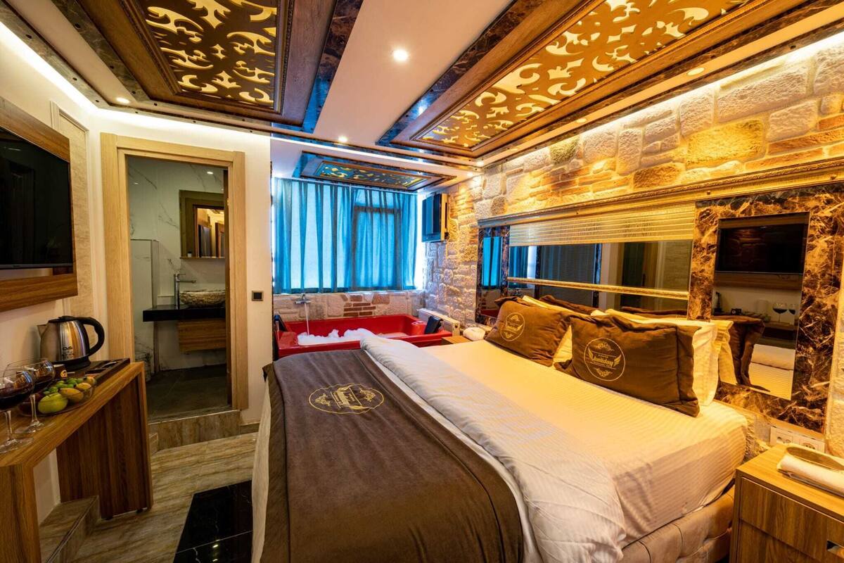 Ein Hotelzimmer mit Bett, Fernseher, einer Steinsäule und einem Fenster mit Vorhängen.