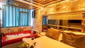 A hotel room with a stone wall, a red bathtub, a bed with brown pillows, and a window with curtains. - Holiday Business Otel (Istanbul)
