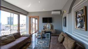 A spacious living room with a large window, a flat-screen TV, a decorative mirror, and a patterned rug. - Holiday Business Otel (Istanbul)