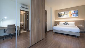 A modern hotel room with a large bed, a desk, and a cityscape painting above the bed. - Dwijaya House of Pakubuwono (Jakarta)