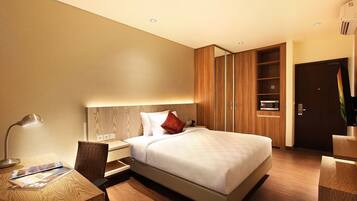 Una habitación de hotel moderna con una cama grande, cabecera de madera, mesitas de noche, un escritorio y un armario.