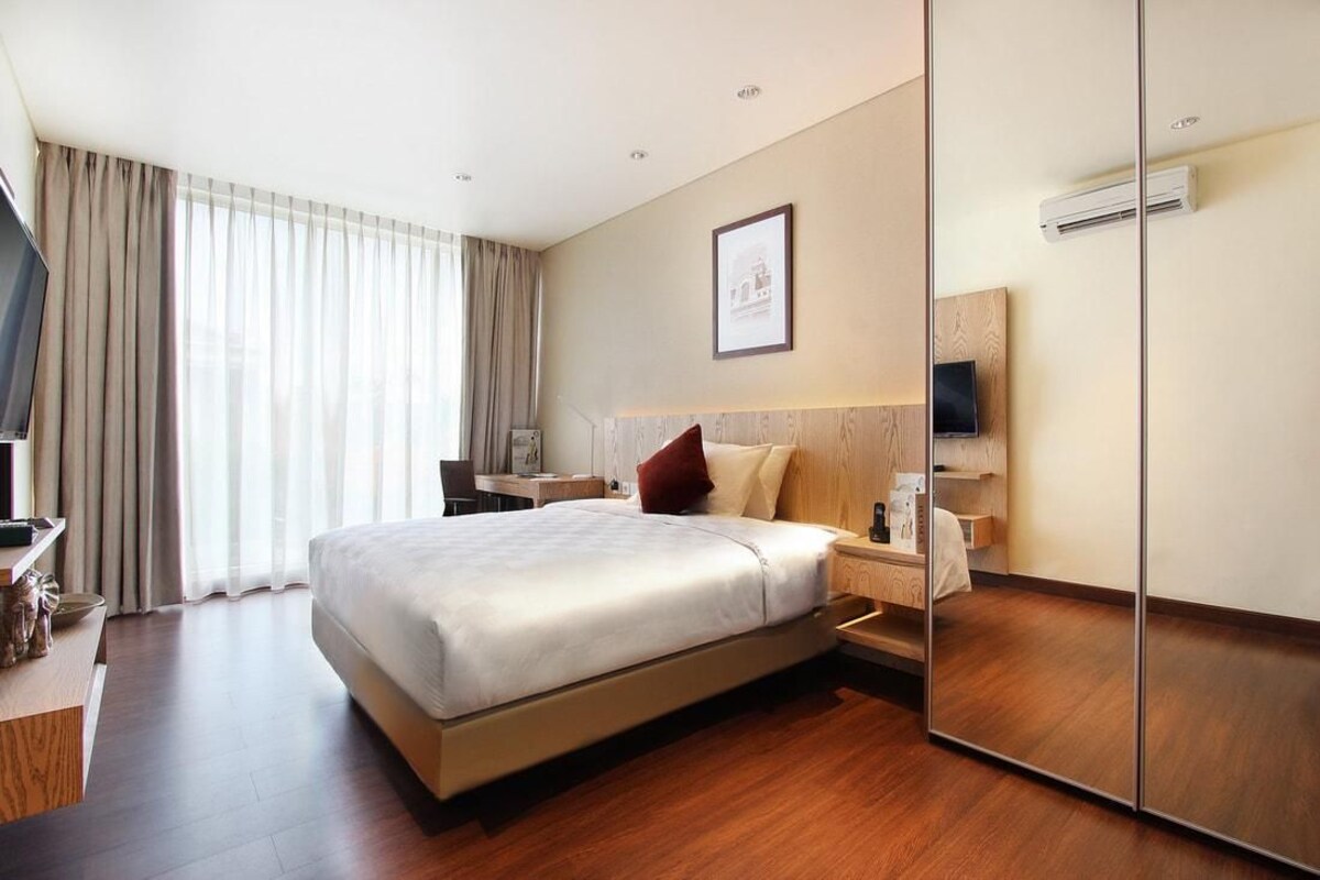 Une chambre d’hôtel avec un grand lit, des tables de chevet, une télévision et un miroir.