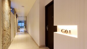 A hallway with a stone wall on one side and a door labeled "G01" on the other. - Dwijaya House of Pakubuwono (Jakarta)