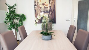 A dining table with a potted plant in the center, surrounded by six chairs. - Residenza Flegrea (Naples)