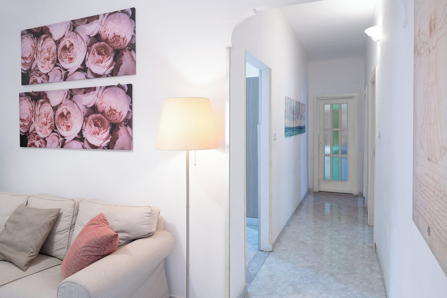 Un couloir avec un canapé et une lampe, qui mène à une porte dotée de panneaux en verre dépoli.