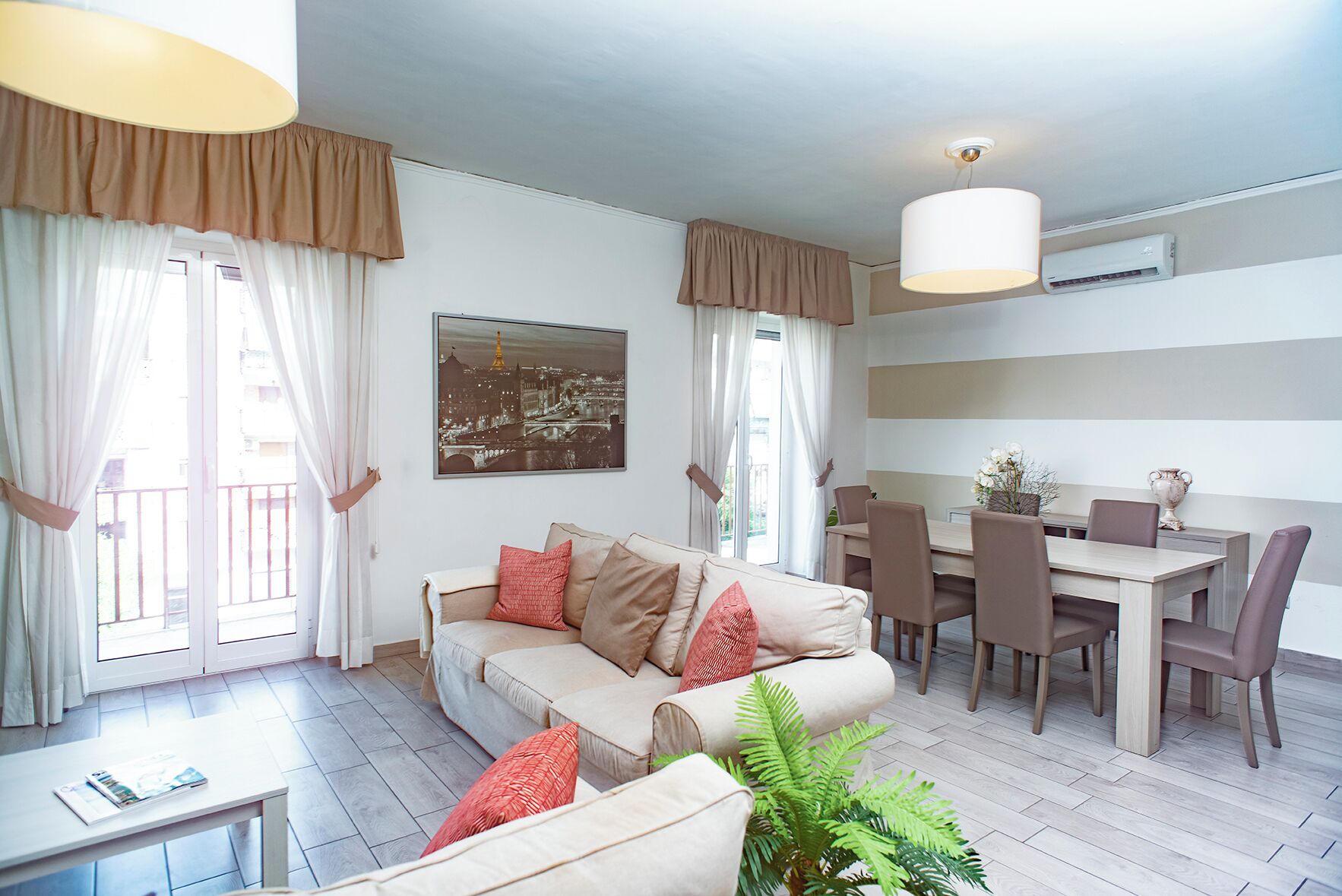 Una sala de estar moderna con un sofá, una mesa de comedor, sillas y una planta en maceta.