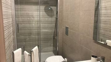 A modern bathroom with a glass-enclosed shower, a toilet, and a sink.