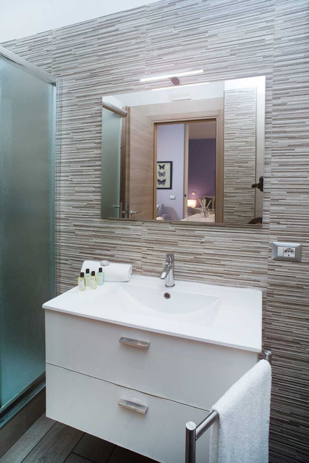 Une salle de bain avec un lavabo blanc, un miroir et un porte-serviettes.