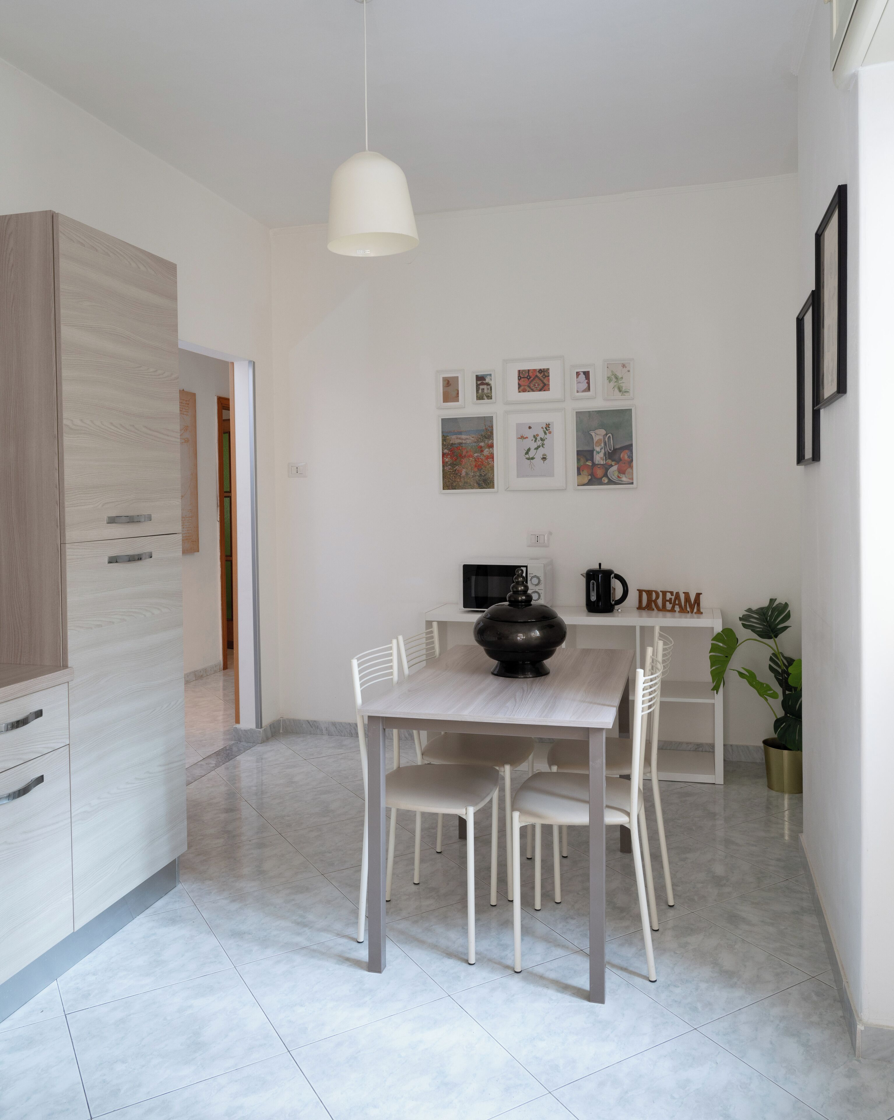 Una cucina moderna con un tavolo da pranzo, sedie, una lampada a sospensione e una macchina per il caffè.