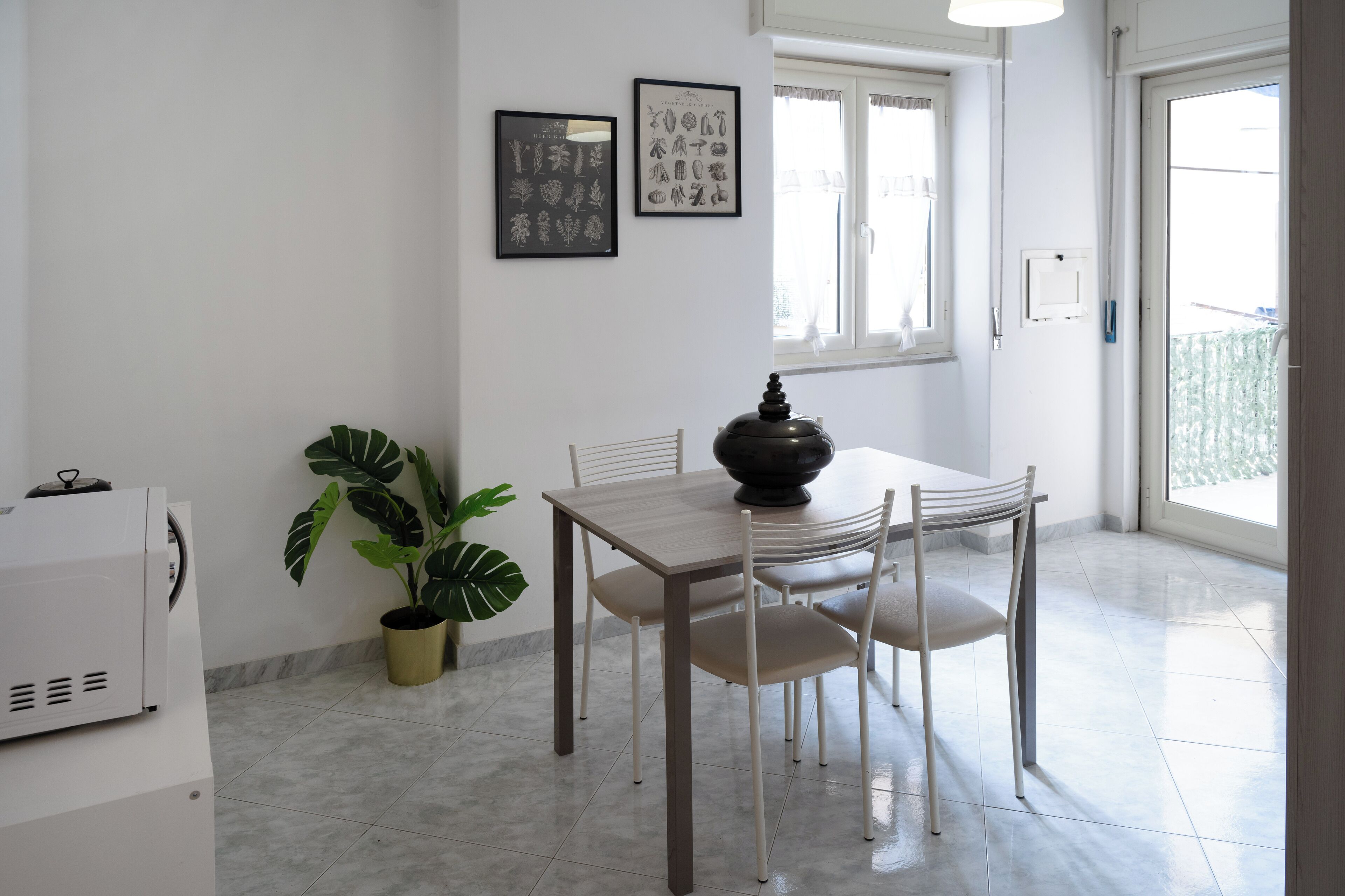 A dining area with a table and chairs, a potted plant, and framed artwork on the wall.