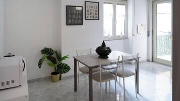 A dining area with a table and chairs, a potted plant, and framed artwork on the wall.