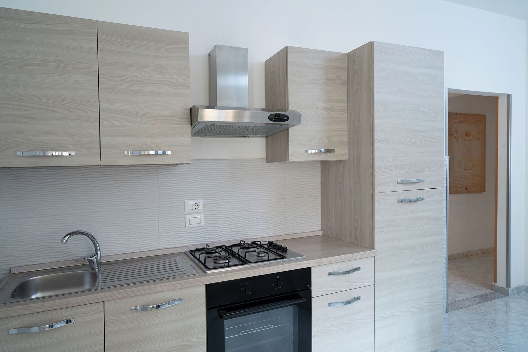 Una cocina moderna con armarios de madera clara, electrodomésticos de acero inoxidable y un salpicadero de azulejos.
