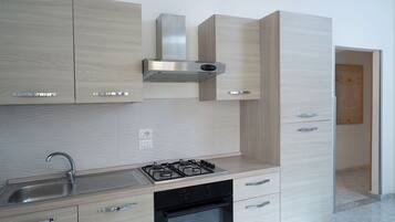 Una cocina moderna con armarios de madera clara, electrodomésticos de acero inoxidable y un salpicadero de azulejos.