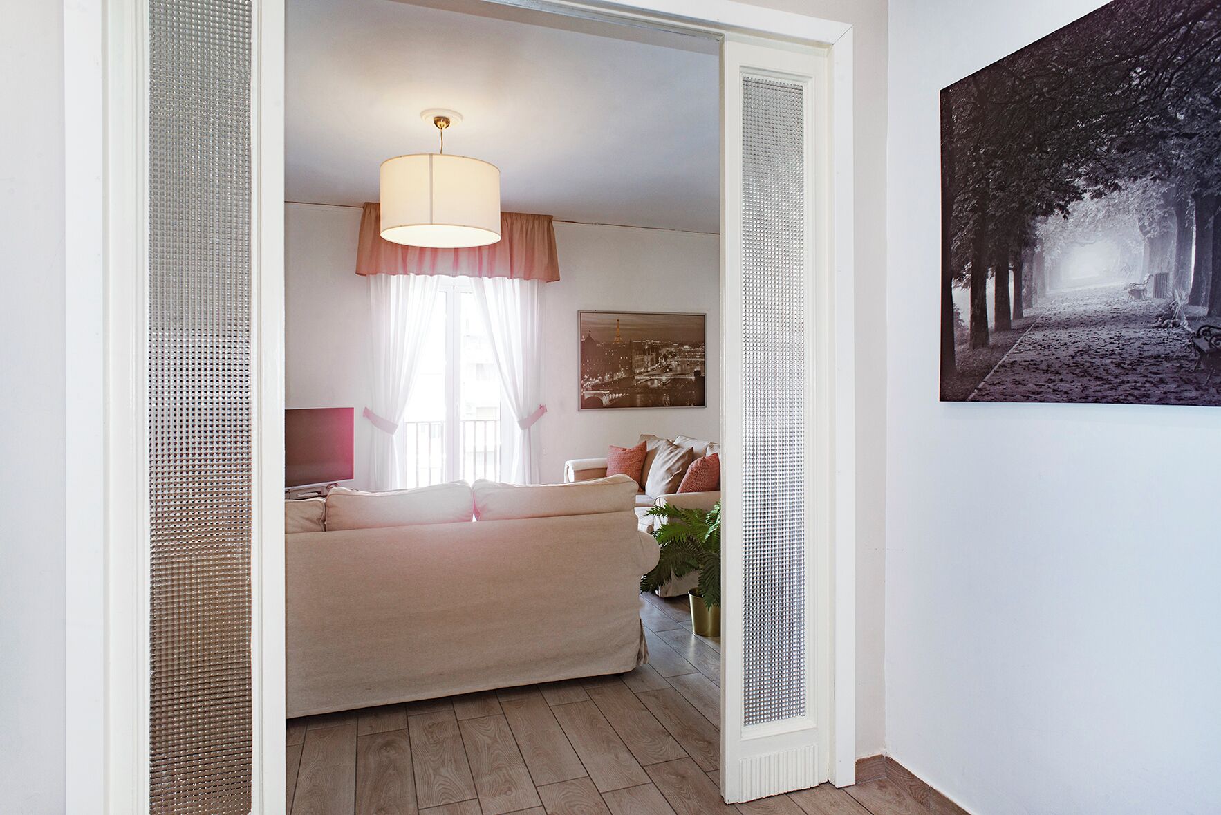 Ein gemütliches Wohnzimmer mit einem beigefarbenen Sofa, einer Hängelampe und einem gerahmten Bild an der Wand.