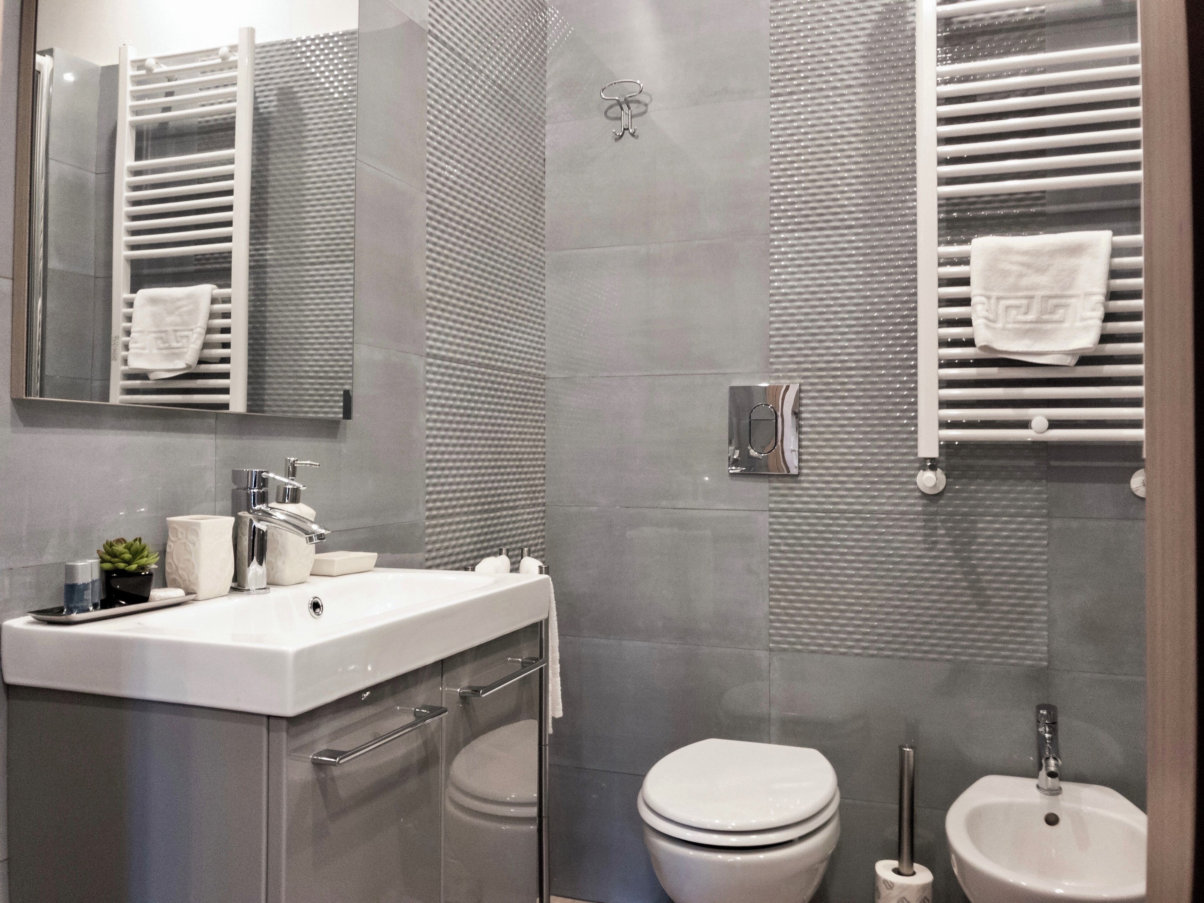 Ein modernes Badezimmer mit Duschkabine aus Glas, Waschbecken mit Spiegel darüber und Toilette mit Bidetfunktion.