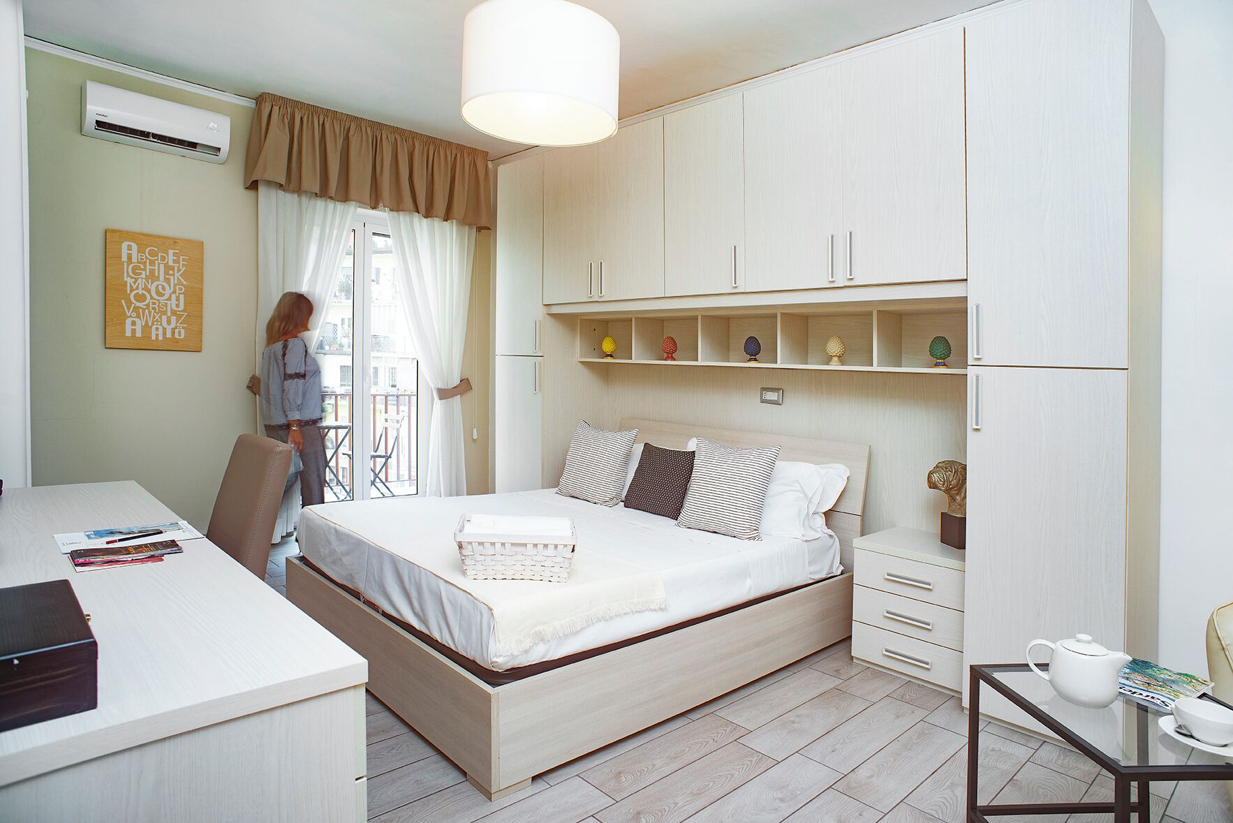 A bedroom with a bed, a desk, and a wardrobe.