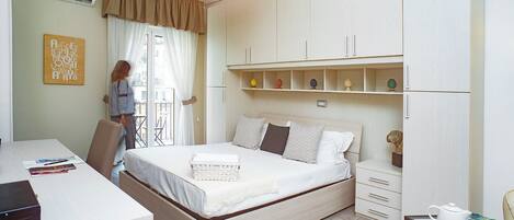 A bedroom with a bed, a desk, and a wardrobe.