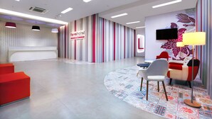 A modern hotel lobby with a reception desk, red and white striped walls, a flat-screen TV, and a patterned rug. - favehotel Sudirman Bojonegoro (Bojonegoro)