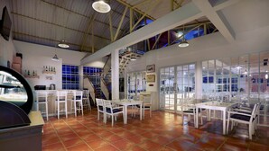 A spacious room with a high ceiling, tiled floor, and multiple tables and chairs arranged for dining. - favehotel Sudirman Bojonegoro (Bojonegoro)