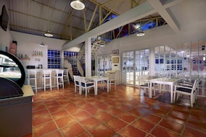 A spacious room with a high ceiling, tiled floor, and multiple tables and chairs arranged for dining. - favehotel Sudirman Bojonegoro (Bojonegoro)