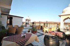 Eine Dachterrasse mit Sitzgelegenheiten im Freien, Topfpflanzen und Blick auf die Stadtlandschaft.