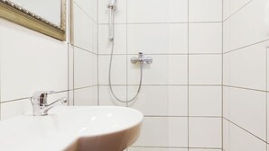 A modern bathroom with a white sink, a shower, and a small bathtub.