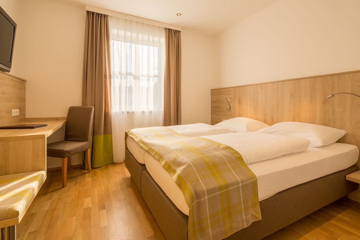 Une chambre d’hôtel avec un lit, un bureau et une chaise.