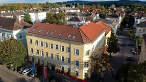 Un hôtel avec un toit recouvert de tuiles rouges, de nombreuses fenêtres et une enseigne indiquant « Hôtel Unter den Linden ».
